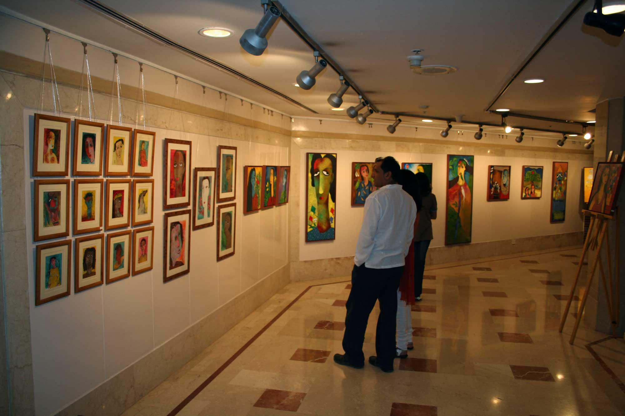 Ratnakar Ojha art exhibition in Leela Palace Mumbai 2007 displaying multiple of his framed paintings and portraits on gallery walls, with visitors viewing the artwork