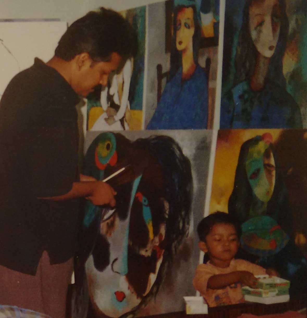 Ratnakar Ojha painting a large-scale portrait artwork in his studio along side his son